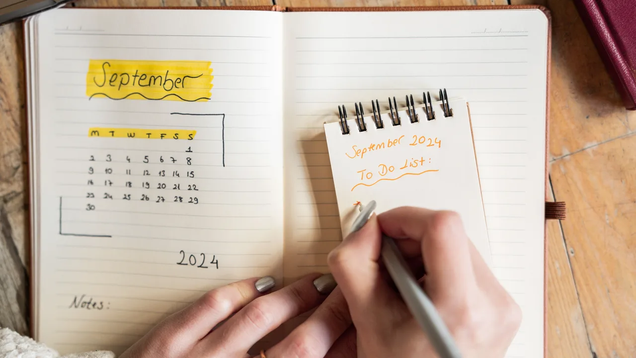 Hand trägt Termine in einen Kalender im Notizbuch ein