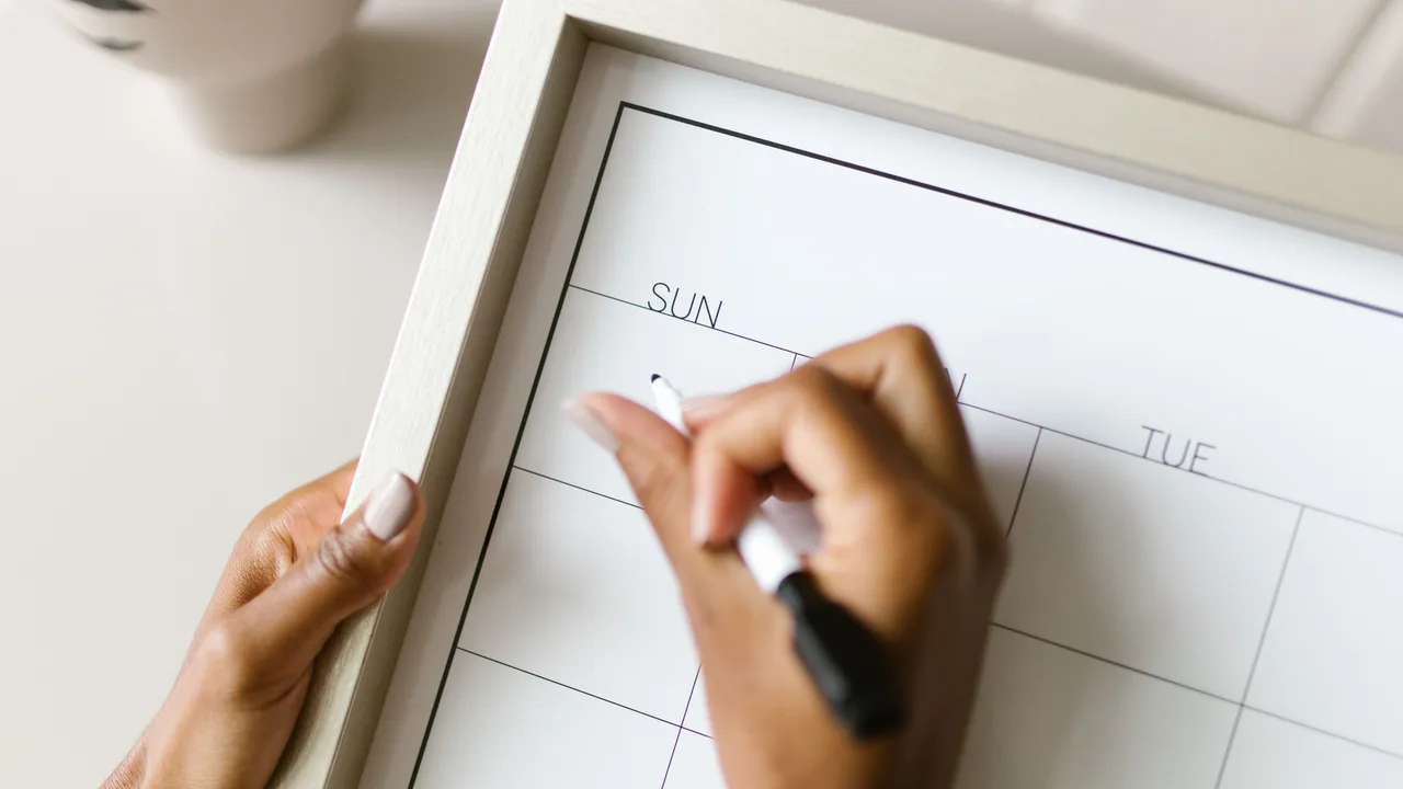 Hand schreibt in einen Wochenplan