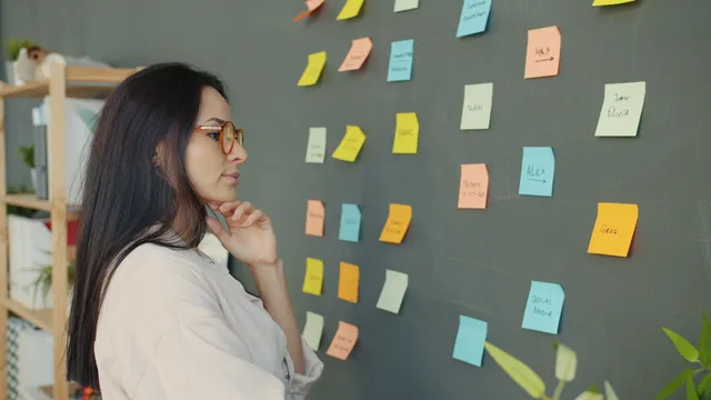 Frau plant mit Haftnotizen an einer Wand