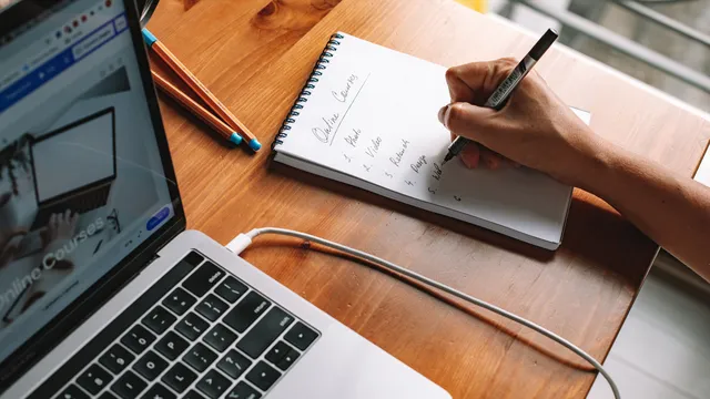 Laptop und Notizbuch beim Lernen am Schreibtisch