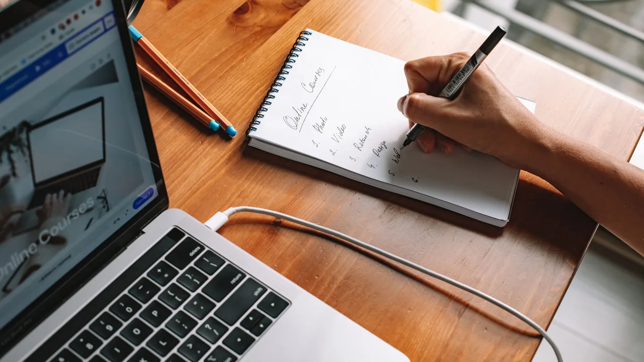 Laptop und Notizbuch beim Lernen am Schreibtisch