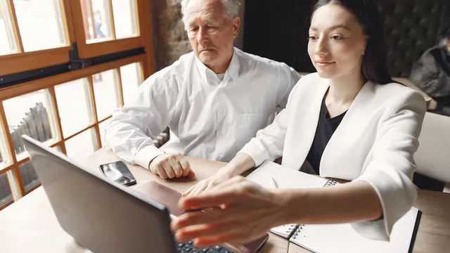 Älterer Kollege und junge Kollegin arbeiten gemeinsam am Laptop